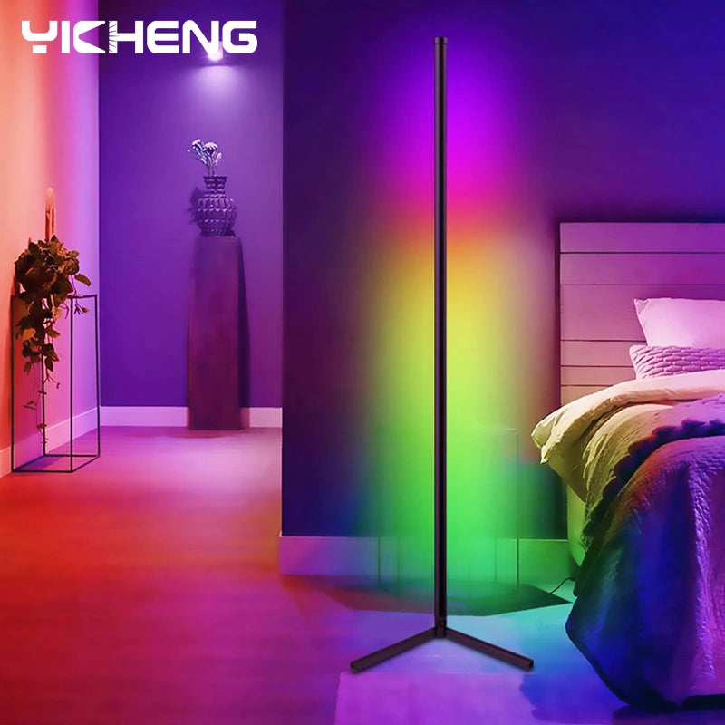 A modern bedroom illuminated by the 180CM RGBIC LED Smart Floor Lamp from BESPOKE SPACE, casting a vibrant spectrum of colors from red to green to blue onto the wall. The room features a bed adorned with white pillows and sheets, a bedside table holding a vase, and a candle-lit shelf on the opposite wall—ideal for contemporary home decor.