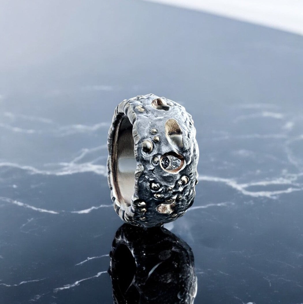 The Lunar Forge Meteorite Ring by Bespoke Space combines the beauty of the moon’s rugged surface with celestial craftsmanship. Each ring is handcrafted from a custom wax model, cast in solid silver or gold, featuring high-definition lunar craters and authentic meteorite fragments